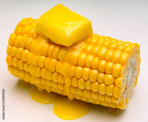 Corn on the cob with melted butter against white background