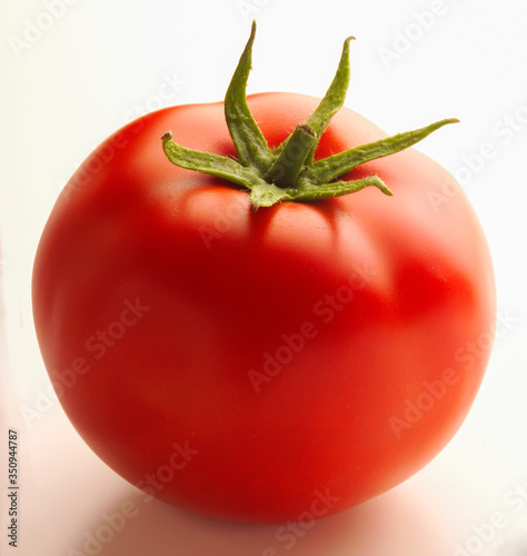 Whole ripe tomato with stalk against white background