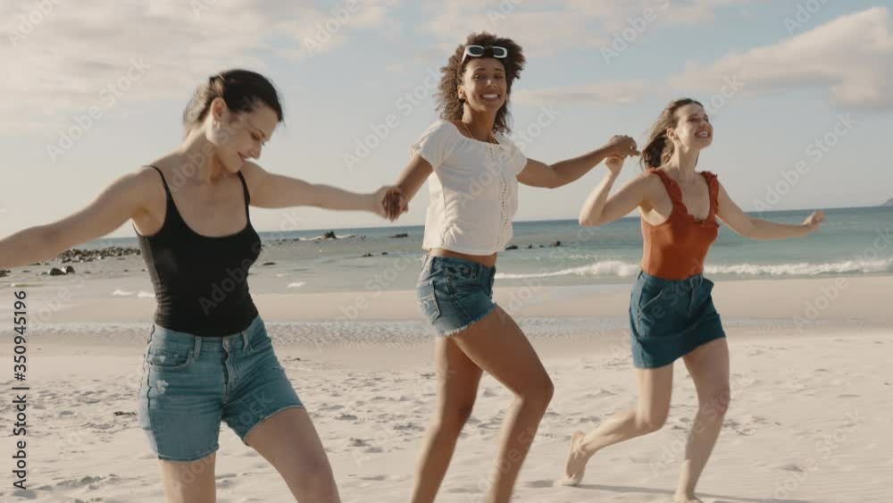 Group of three women walking together holding hands at the beach. Multi-ethnic group of friends enjoying themselves on the beach.
Group of three women walking together holding hands at the beach. Multi-ethnic group of friends enjoying themselves on the beach.