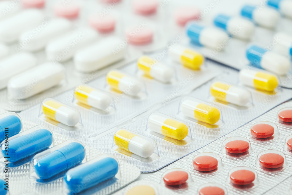 pile of medical pills in red, blue and yellow colors in silver plastic packaging pile of medical pills in red, blue and yellow colors in silver plastic packaging