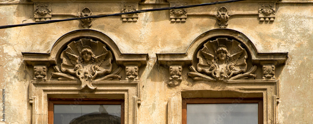details of decorative ornament on plaster over the windows of an old building