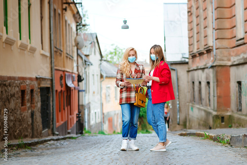 Summer vacation after coronavirus lockdown. Tourists girls wearing face masks at street. © volurol