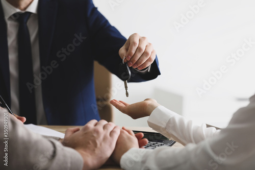 Salesman giving key to customers in office, closeup. Buying new car