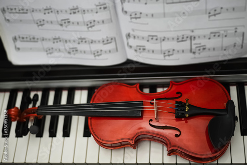 Violin put on piano keys.in front of blurred sheet note,prepare for practicing,blurry light around