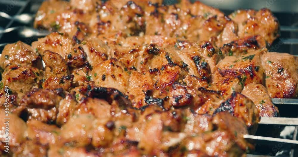 Meat Grilled on Skewers on the Grill on the Street Market. Tasty grilled food. Pork meat prepared on fire. Street food. Barbecue party. Roasted meat with crust. Close up, 4k. Meat Grilled on Skewers on the Grill on the Street Market. Tasty grilled food. Pork meat prepared on fire. Street food. Barbecue party. Roasted meat with crust. Close up, 4k.