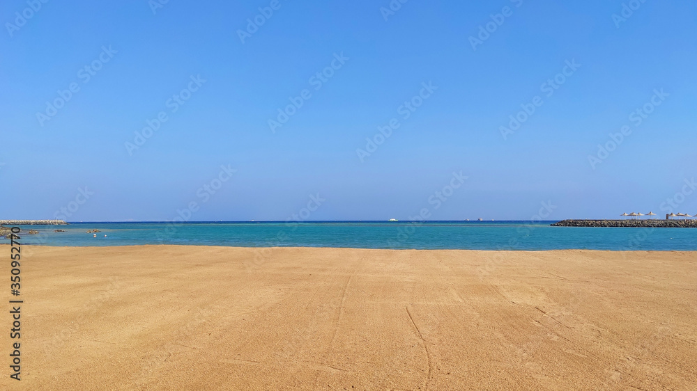 Deserted seashore. Yellow sand and blue water of the sea.