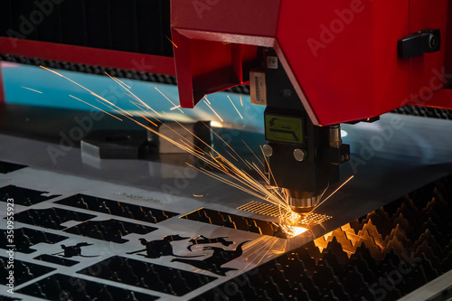 The fiber laser cutting machine cutting the sheet metal plate with the sparkling light. The hi-technology sheet metal manufacturing process by laser cutting machine.