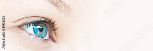 Close up on a girl blue eye, panoramic web banner with copy space