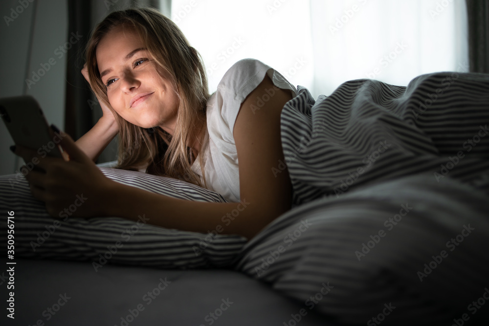 Pretty, young woman sleeping in her bed with her cell phone close to her. Smartphone in Bed Mobile/smartphone Addiction Concept. Pretty, young woman sleeping in her bed with her cell phone close to her. Smartphone in Bed Mobile/smartphone Addiction Concept.