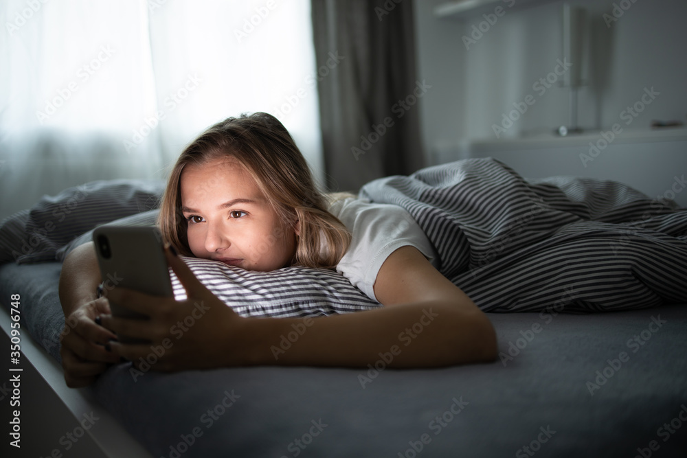 Pretty, young woman sleeping in her bed with her cell phone close to her. Smartphone in Bed Mobile/smartphone Addiction Concept. Pretty, young woman sleeping in her bed with her cell phone close to her. Smartphone in Bed Mobile/smartphone Addiction Concept.