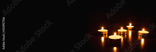 Several burning candles on a black background. Banner with copy space.