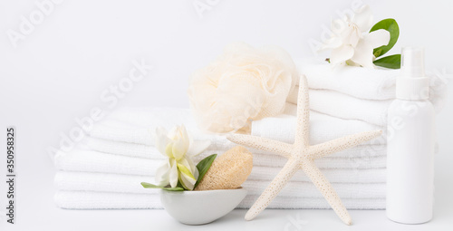 Spa and health care concepts setup with stack of white towels star fish Gardenia flowers spray bottle and loofah scrub on white background