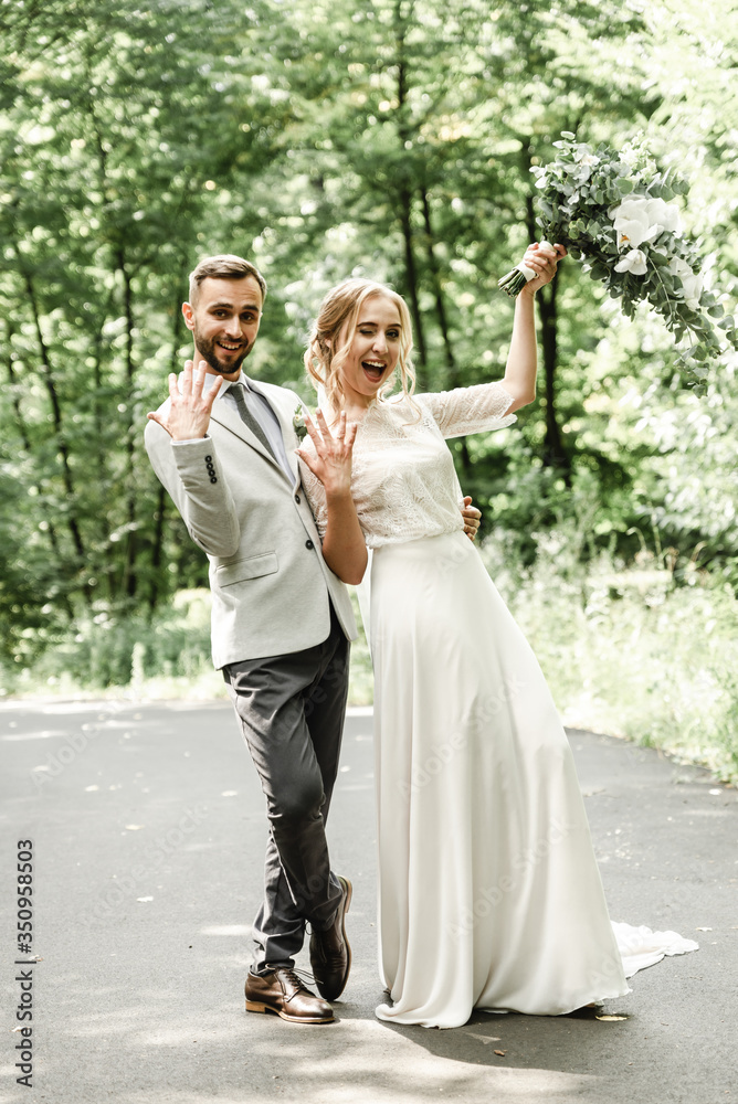 Lovely newlyweds hugging and smiling in a green park. Portrait of the bride and groom in a lace dress. Wedding day of a happy newlywed couple Lovely newlyweds hugging and smiling in a green park. Portrait of the bride and groom in a lace dress. Wedding day of a happy newlywed couple