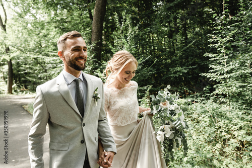 Just married couple dancing valse outdoors, free space. Bride and groom hug, blurred green grass background. The first concept of wedding dance photo