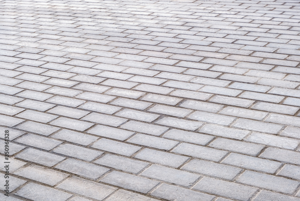 Texture of gray patterned paving tiles on the ground of street, perspective view. Concrete paving slab flagstone. Cement brick squared stone floor background. Sidewalk pavement pattern.