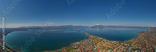 Sirmione town, Lake Garda, Italy. Aerial view of Sirmione high altitude. In the background mountains in the snow and blue sky. Aerial panorama