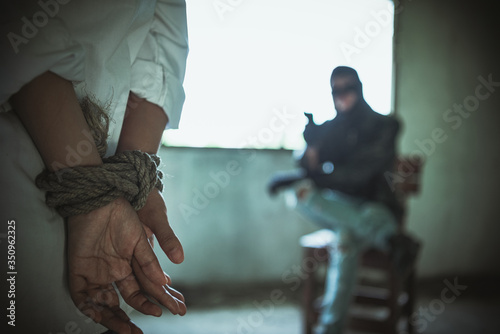 Canvastavla Back view of hostage woman with tie rope in hands,The thief pointed his gun towards him