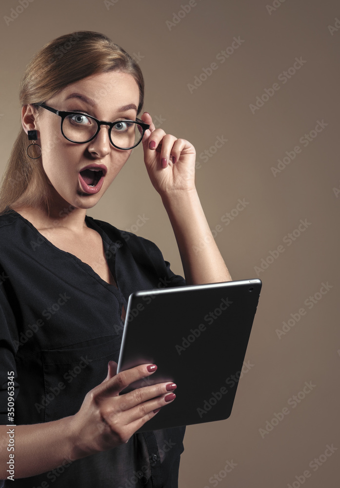 Vertical Portrait of surprised Young girl wearing eyeglasses and holding digital tablet