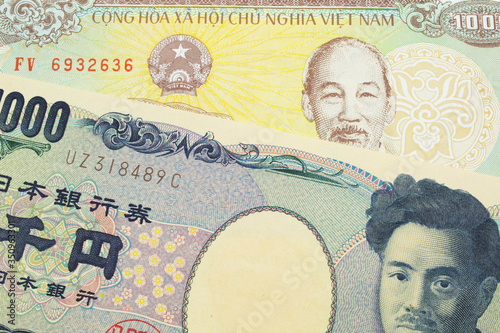 A macro image of a Japanese thousand yen note paired up with a yellow one thousand dong bill from Vietnam. Shot close up in macro.