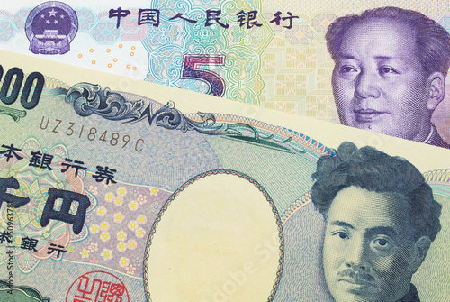 A macro image of a Japanese thousand yen note paired up with a purple, blue and white five yuan bank note from China. Shot close up in macro.