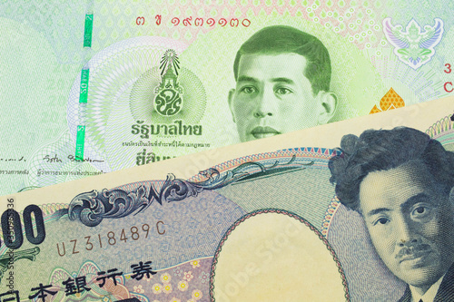 A macro image of a Japanese thousand yen note paired up with a green twenty baht bank note from Thailand. Shot close up in macro.