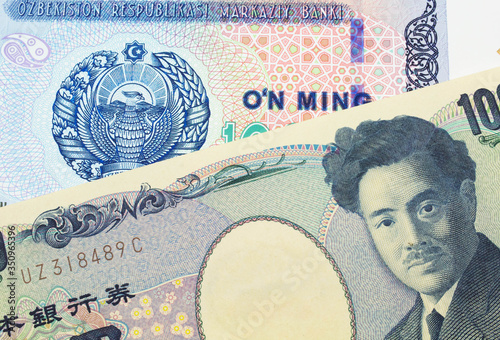 A macro image of a Japanese thousand yen note paired up with a blue, white and green ten thousand som note from Uzbekistan. Shot close up in macro.