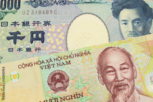 A macro image of a Japanese thousand yen note paired up with a colorful, plastic ten thousand dong note from Vietnam. Shot close up in macro.