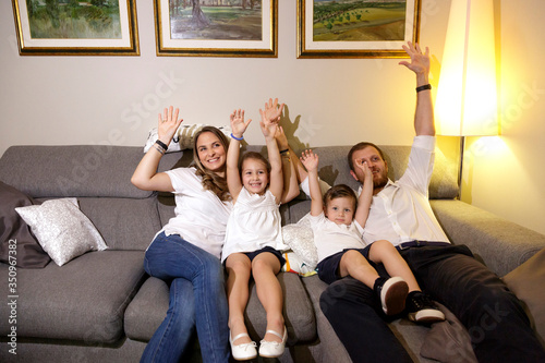 gruppo familiare alza le braccia allegramente a casa nel divano  photo