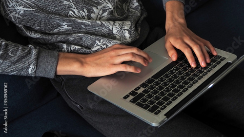 Work at the computer. Men's hands press the keys of a laptop. Photo in dark colors