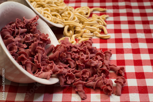 Raw italian pasta in a red and white towel background top view