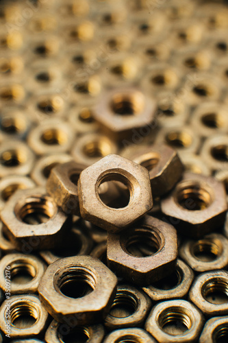Close-up, macro. Old soviet brass nuts. Texture, background of brass nuts laid out in the form of honeycombs. Nuts of gold color. Dirty nuts in oil. Brass scrap metal