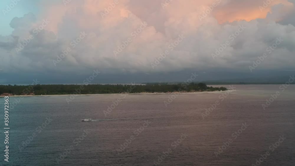 a boat departs from the island with beautiful blue-orange clouds and the mainland is visible on the horizon a boat departs from the island with beautiful blue-orange clouds and the mainland is visible on the horizon