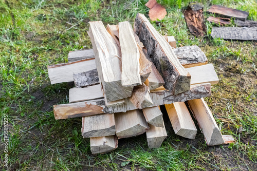 chopped wood is lying on the grass. Harvesting wood for the winter and for lighting a fire. The problem of deforestation and Ecological problems concept