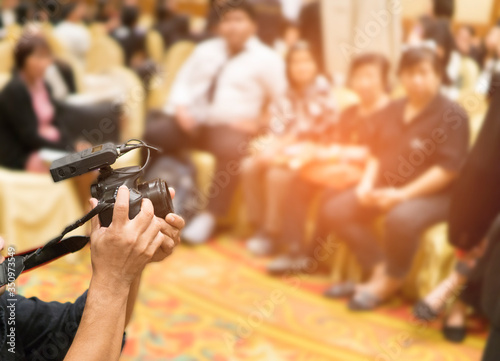 Photographer video recording activity within the event meeting room.blurred background.Video camera with hands working equipment