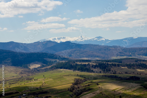 View of the Carpathian Mountains landscape in cloudy summer day. Mountain peaks, forests, fields and meadows, beautiful natural landscape