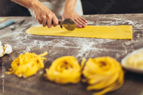 Woman cutting dough for ravioli on table