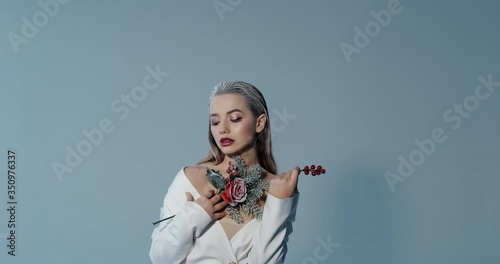 Girl with makeup poses for photographer in studio, photo studio, winter look, bright lips, white hair, New Year photo shoot, professional model, cold look, is photographed with an artificial flower