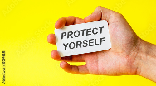 Businessman holds a card with the text protect yourself on a yellow background