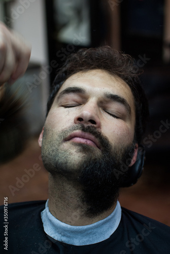 Handsome man trimming beard at barbershop