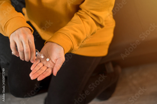 Closeup of a caucasian woman pouring pills from a jar into her hand to treat the virus. The concept of taking medicine on schedule