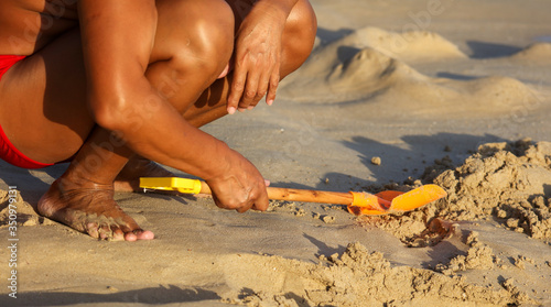 A man plays in the sand with a shovel on the beach near the sea.
