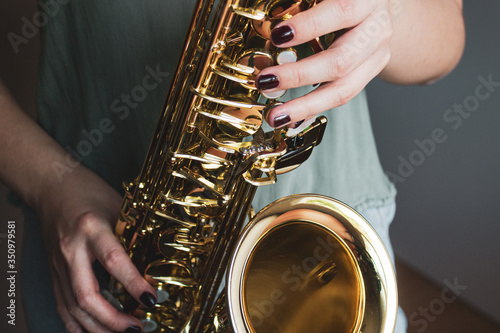 Saxophone girl player hands. Saxophonist playing jazz music. Alto sax musical instrument closeup. Painted nails.