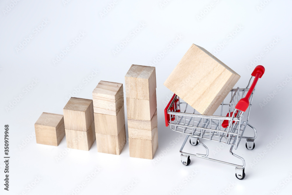 Graphs chart wooden cube block and trolley cart on a white background. Shopping, sale, finance, and business concept. Graphs chart wooden cube block and trolley cart on a white background. Shopping, sale, finance, and business concept.