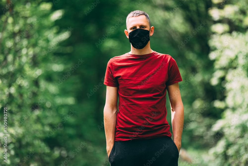 Young man in black face mask in the forest. breathing of fresh air during pandemic.