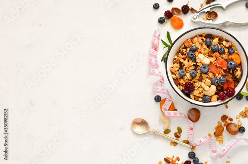 Healthy breakfast - organic granola with honey, oatmeal, cashew nut, almond, raisin and strawberries, blueberries on a white background. The concept of diet.copy space.