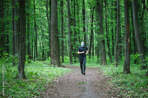 Runner wearing medical mask. Coronavirus pandemic Covid-19 a man in a medical mask runs in the forest