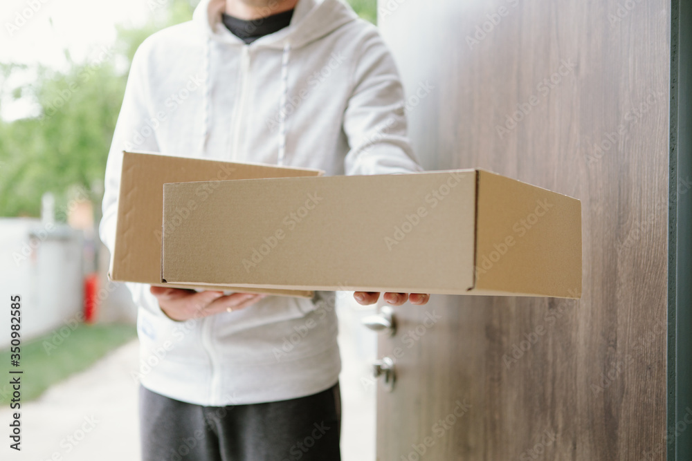 Home delivery shopping box man wearing gloves and protective mask delivering packages at door. Home delivery shopping box man wearing gloves and protective mask delivering packages at door.