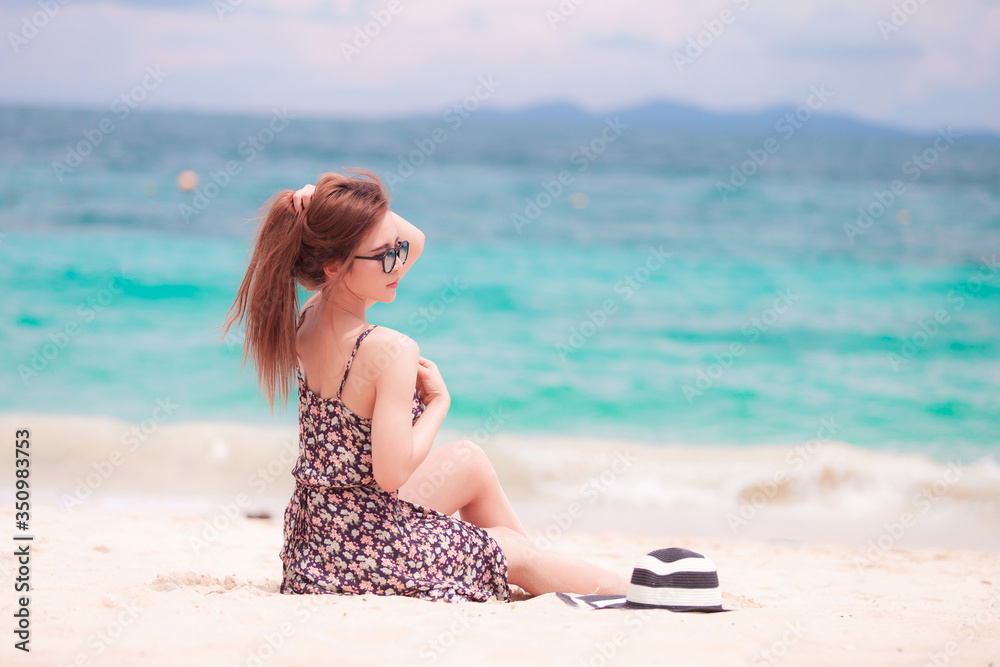 Young beautiful sexy woman relaxing on the white sandy beach near the waves of blue on tropical beach background near ocean / Summer concept Young beautiful sexy woman relaxing on the white sandy beach near the waves of blue on tropical beach background near ocean / Summer concept