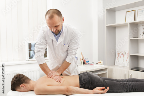 Manual therapist doing manual adjustment on patient's spine. Chiropractic, osteopathy, manual therapy, post traumatic rehabilitation, sport physical therapy. Alternative medicine, pain relief concept. photo