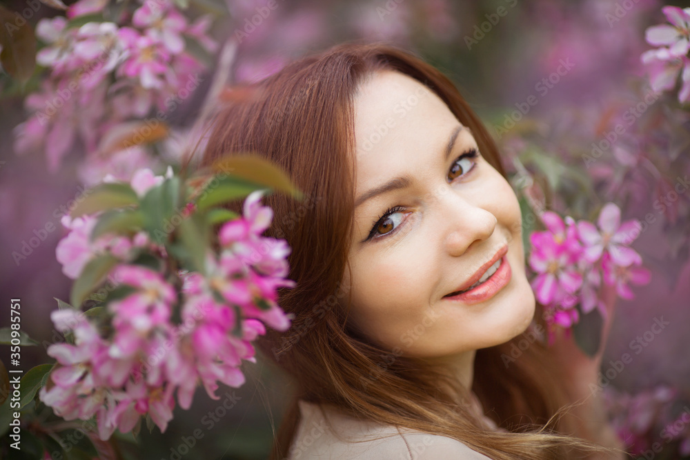 portrait of a beautiful young woman with make-up near a tree with flowers